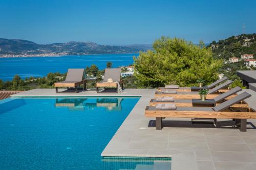 a swimming pool with benches and a view of the water at Echos Villa in Argostoli