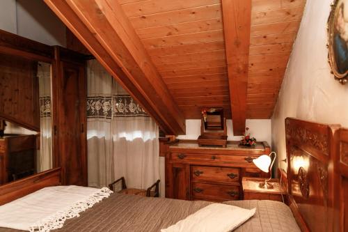 Casa montagna CIELO BLU في أولكس: غرفة نوم بسرير وسقف خشبي