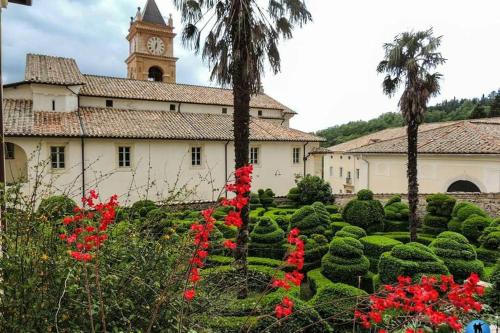 a building with a clock tower and a garden with red flowers at La Piega in Collepardo