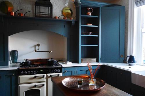 a kitchen with blue cabinets and a stove and a table at Luxury 2 bed Georgian Townhouse, Old Portsmouth in Portsmouth