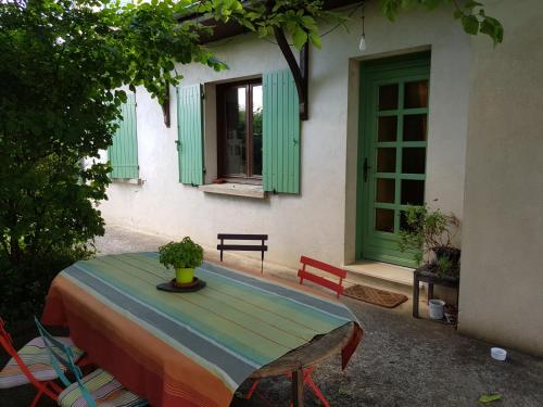a table and chairs in front of a house with green windows at Chambre avec salle de bains privative in Boutiers-Saint-Trojan