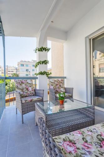 a balcony with a glass table and chairs at Downtown Larnaca in Larnaka