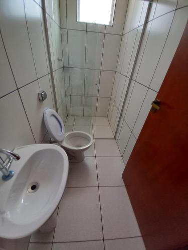 a white bathroom with a sink and a toilet at Apartamento avenida 06 com ar condicionado in São Thomé das Letras