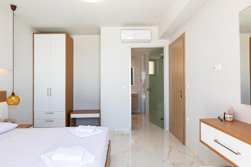 a white bedroom with a bed and a mirror at Falasarna village in Falasarna