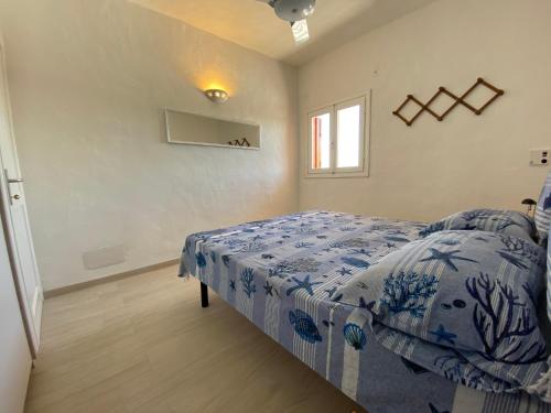 Schlafzimmer mit einem Bett mit einer blauen und weißen Bettdecke in der Unterkunft Appartamento in Costa Smeralda - Bilocale sul mare - Sea View in Olbia