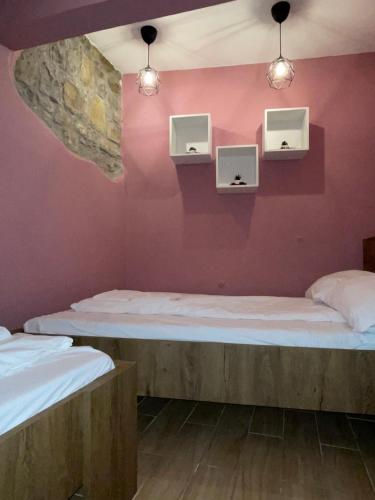two beds in a room with pink walls and lights at Apartment ILI in Piran