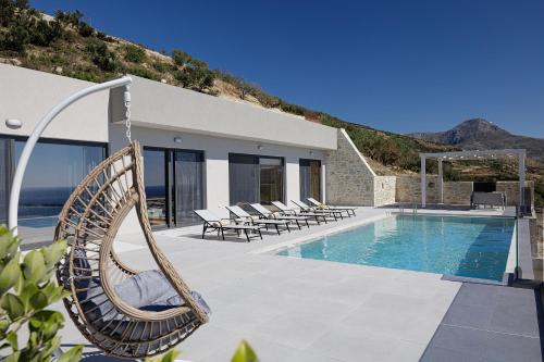 a swinging rattan chair next to a swimming pool at Falasarna village in Falasarna