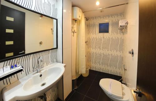 チェンナイにあるHotel Gokulam Parkの洗面台、トイレ、鏡のあるバスルーム