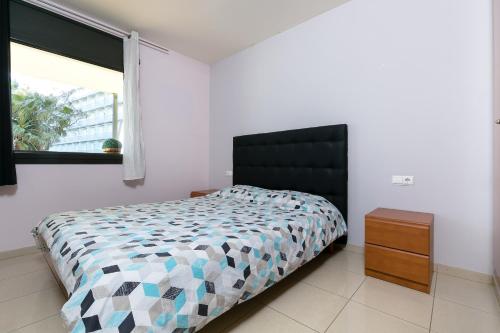 une chambre avec un lit avec une tête de lit noire et une fenêtre dans l'établissement the beach milenium, à Roses