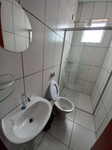 a white bathroom with a sink and a toilet at Apartamento avenida 07 com ar condicionado in São Thomé das Letras