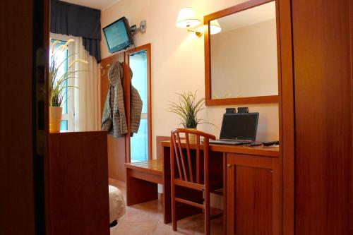a room with a desk with a laptop and a mirror at Hotel Jole in Cesenatico
