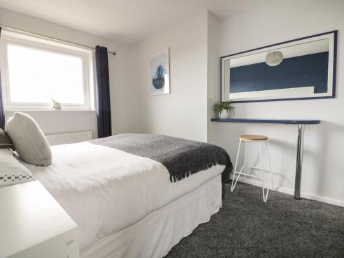 a bedroom with a white bed and a stool at Estuary View in Newquay