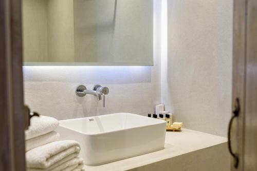 a bathroom with a white sink and towels on a counter at Hotel Senia - Onar Hotels Collection in Naousa