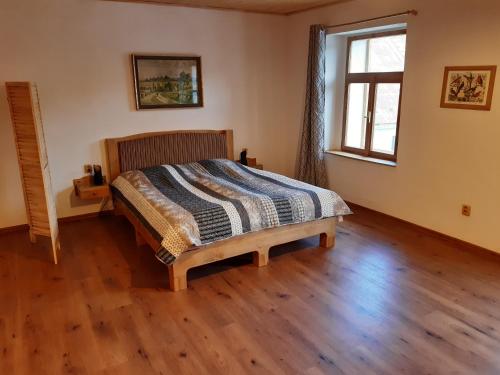 a bed in a room with a wooden floor at Stáj Zakšín - špejchar in Dubá