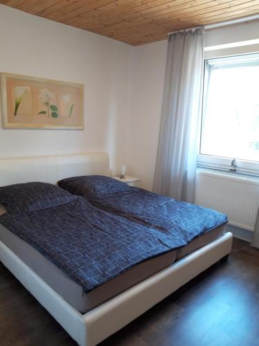 a bedroom with a bed with a blue comforter and a window at Apartment in Bad Schwartau in Bad Schwartau