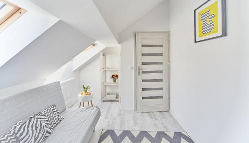 biały korytarz na poddaszu z białymi drzwiami i schodami w obiekcie Porta Mare Apartments LuxView III w Dziwnówku