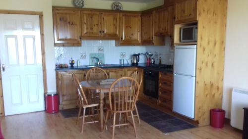 a kitchen with wooden cabinets and a table and chairs at Apartment No. 3 Bunbeg in Bunbeg