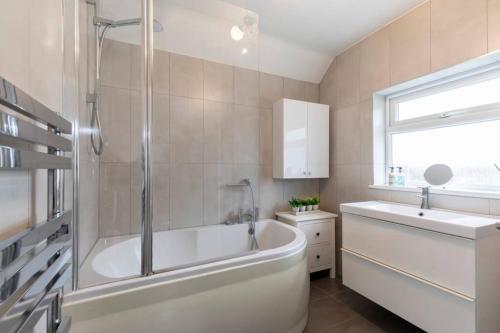 a white bathroom with a tub and a sink at Modern Three Bedroom Home in Gloucester with Hot Tub in Gloucester