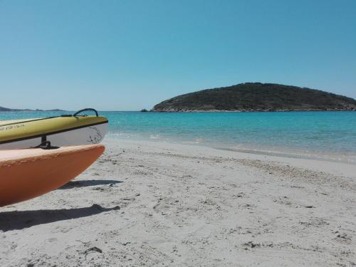 a boat on a beach with an island in the water at Casa vacanze Sardegna " Tzia Maurissia " in Teulada