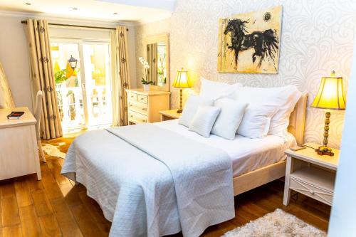 a bedroom with a large white bed with a horse painting on the wall at Resort Fazenda Viegas in Lagos