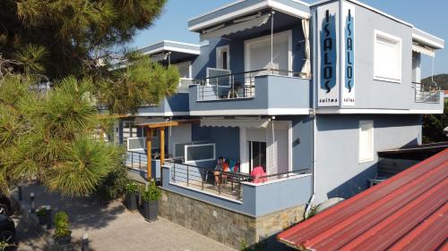 a blue house with two people sitting on the balcony at Isalos Suites in Néa Péramos