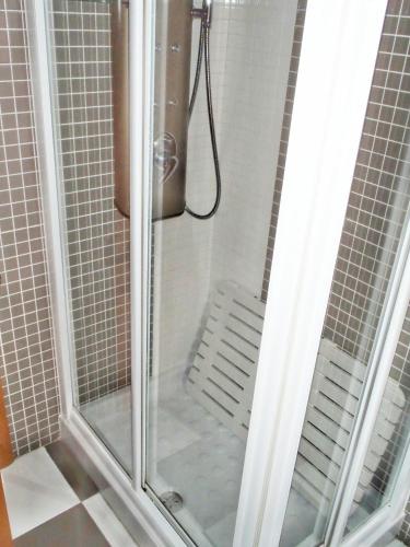 a shower with a glass door with a bench at El Balconcito de San Millán III in Segovia