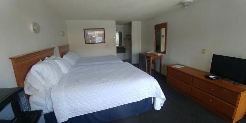 a bedroom with a white bed and a television at Thunderbird Motel in Pocatello