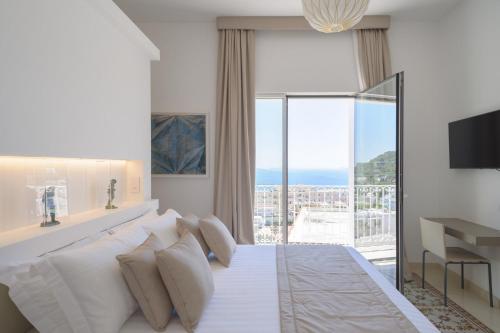 a bedroom with a white bed and a large window at Sopramonte Exclusive Rooms in Capri