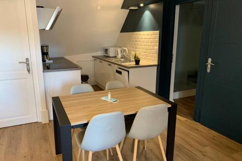 - une cuisine avec une table en bois et des chaises blanches dans l'établissement Le Cheval Bixio, à Beaune