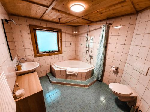 a bathroom with a tub and a toilet and a sink at Ferienhaus Berger in Virgen
