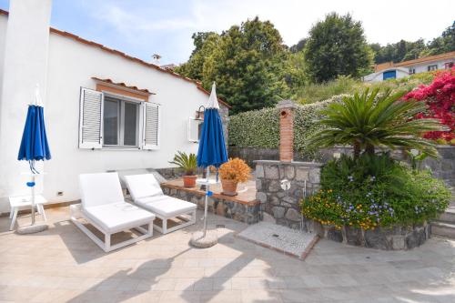 a patio with two blue umbrellas and a table and chairs at Relais Maison de Charles in Ischia