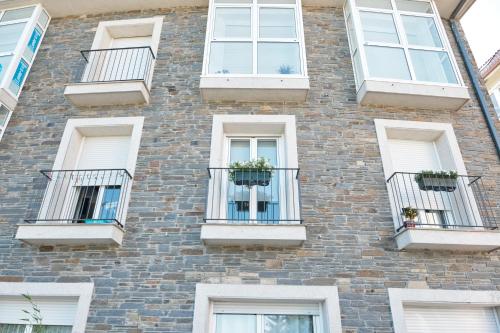 a brick building with white windows and potted plants at Peregrina Pension 3 in O Pedrouzo