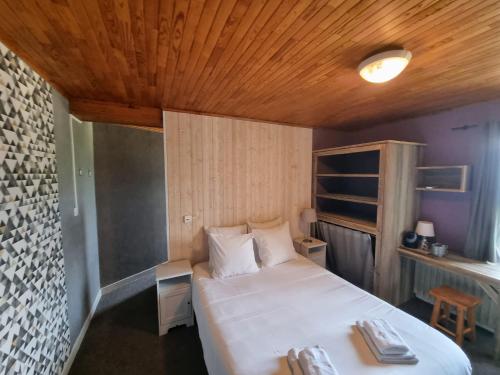 a bedroom with a white bed and a wooden ceiling at Hotel Le Beau Site in Auris