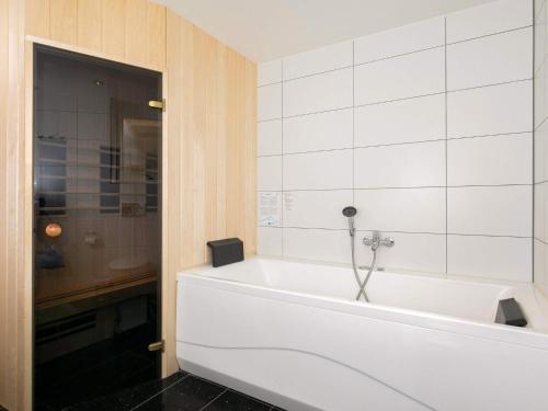 een badkamer met een bad en witte tegels bij 10 person holiday home in Brovst in Tranum Strand
