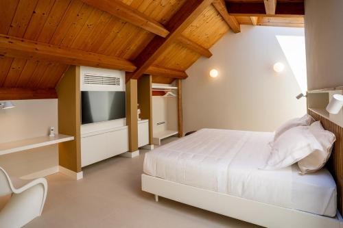 a bedroom with a white bed and a television at Villa Corallo in SantʼOmero