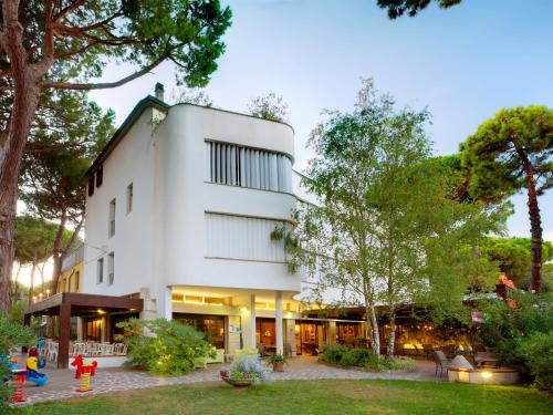 un grand bâtiment blanc avec des arbres devant lui dans l'établissement Hotel Columbia, à Marina Romea