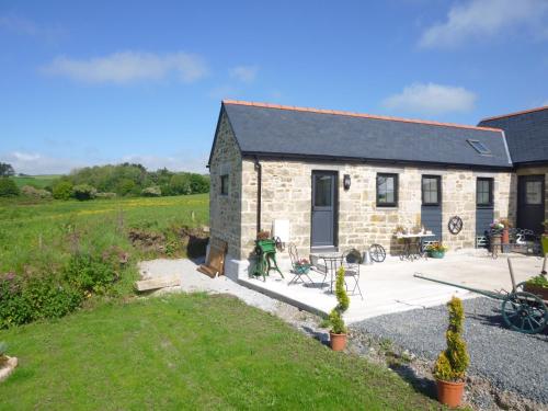 a stone cottage with a patio and a yard at Medlyn moor retreats in Porkellis
