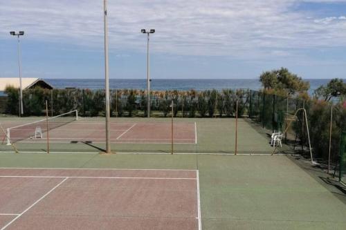 zwei Tennisplätze mit Meerblick im Hintergrund in der Unterkunft Studio 4 personnes bord de mer avec piscine wifi in Cervione
