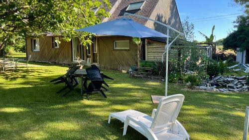 a yard with a table and chairs and an umbrella at Entre terre et mer in Combrit