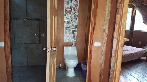 a small bathroom with a toilet and a shower at Utopia Eco Hotel in Lanquín