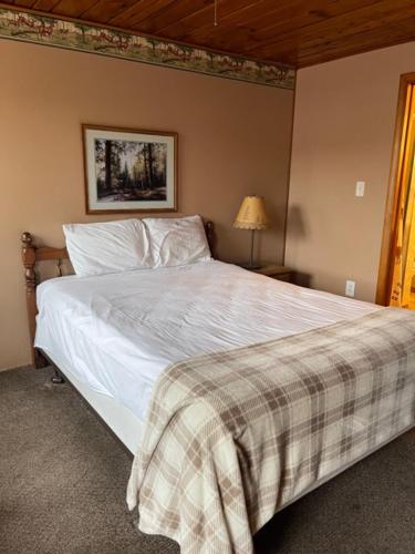 een slaapkamer met een wit bed en een geruite deken bij The Terrace Motel in Munising