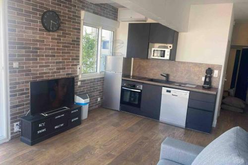 une cuisine avec une télévision et un mur de briques dans l'établissement NEW YORK, à La Grande Motte