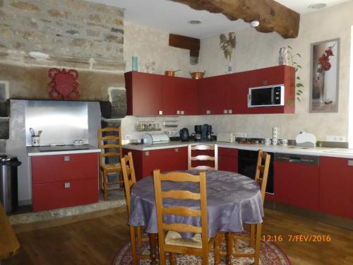 a kitchen with red cabinets and a table and chairs at Le Logis de la Cour de Bretagne au Port de Dinan Lanvallay in Lanvallay