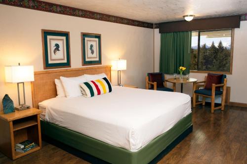 ビッグフォークにあるTimbers Motelのベッド、テーブル、椅子が備わるホテルルームです。