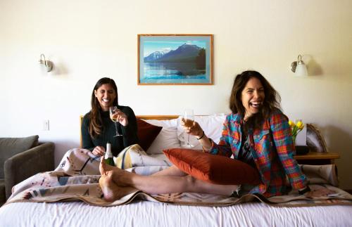 ビッグフォークにあるTimbers Motelの二人の女性がワインを飲みながらベッドに座っている