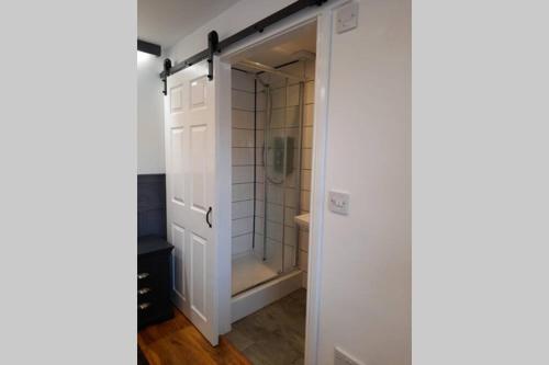 ein Bad mit einer Dusche und einer Glastür in der Unterkunft THE CLOCKHOUSE, ROuGHTON in Roughton