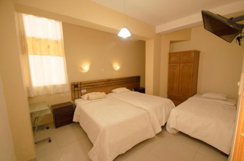 Hotel Piura Sol de Grau في بيورا: غرفة نوم بسريرين وتلفزيون فيها