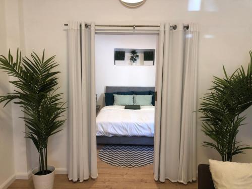 a bedroom with a bed with white curtains and two plants at Villa Tlv רחוב הירקון 27 תל אביב in Tel Aviv