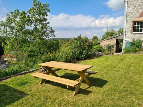 una mesa de picnic de madera en el césped en Maison de campagne avec superbe vue panoramique!, en Bousignies-sur-Roc