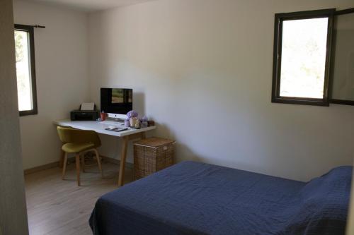 Schlafzimmer mit einem Bett und einem Schreibtisch mit einem Computer in der Unterkunft Villa en Campagne Provençale avec piscine in Curnier